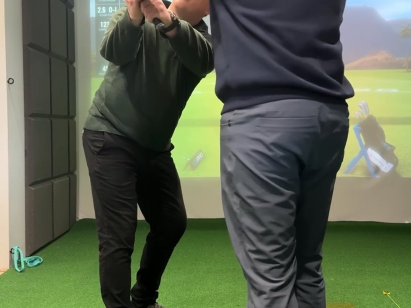 Indoor simulator studio session with launch monitor data on screen at Woodside Golf Club